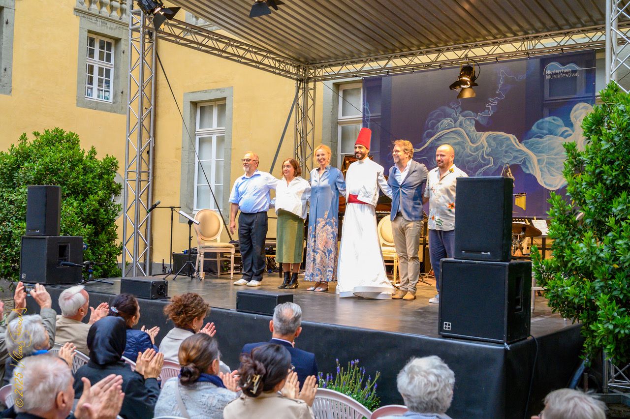 6 Menschen auf einer Open-Air-Bühne verbeugen sich